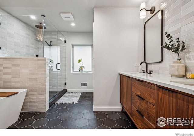 bathroom with double vanity, visible vents, a stall shower, a sink, and a freestanding tub