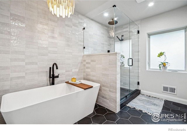 full bath featuring tile walls, visible vents, a shower stall, tile patterned flooring, and a freestanding tub