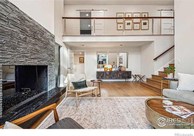 living room featuring a high ceiling, stairway, wood finished floors, and a high end fireplace