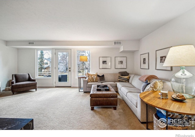 living area with carpet flooring, visible vents, and baseboards