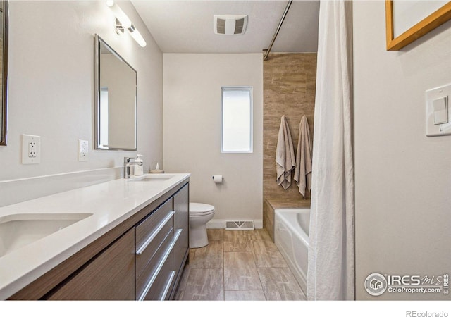 full bathroom featuring toilet, double vanity, a sink, and visible vents