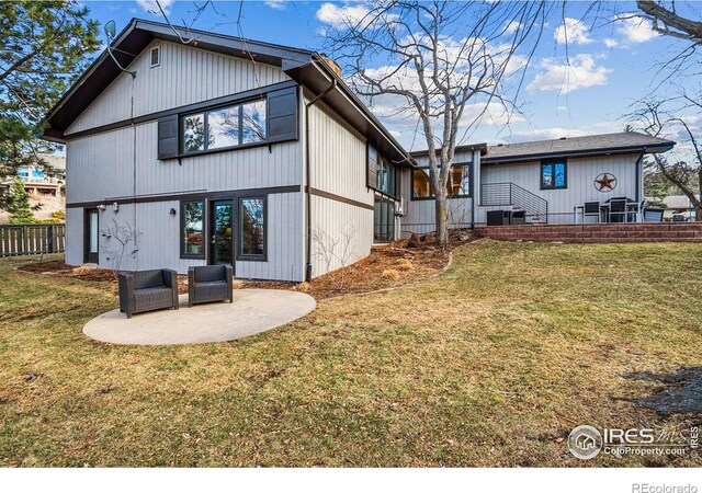 rear view of property featuring a patio, a yard, and fence