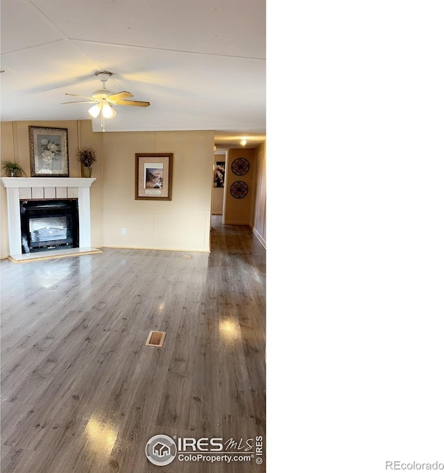 unfurnished living room featuring visible vents, a ceiling fan, a fireplace with raised hearth, and wood finished floors