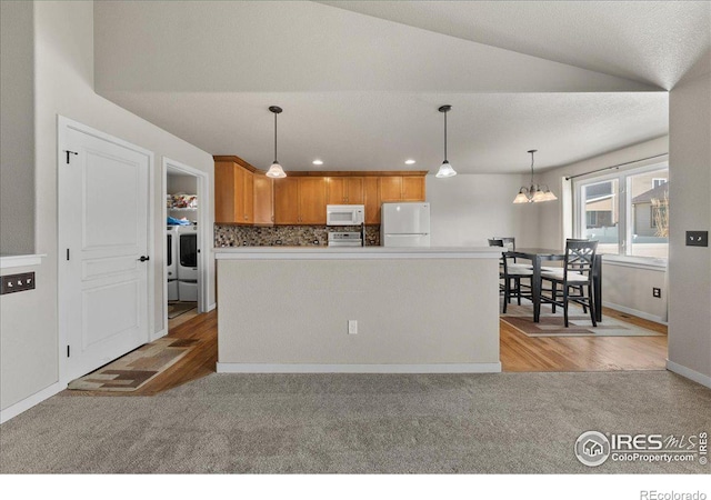 kitchen with white appliances, light carpet, hanging light fixtures, and decorative backsplash