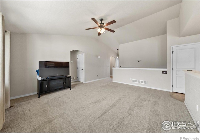 living room with carpet floors, arched walkways, visible vents, a ceiling fan, and vaulted ceiling