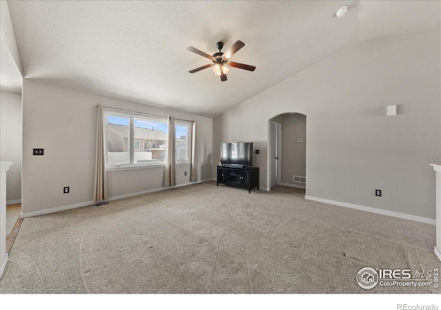 unfurnished living room with carpet floors, arched walkways, lofted ceiling, ceiling fan, and a textured ceiling