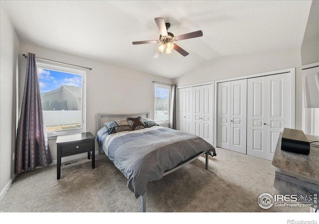 bedroom featuring baseboards, ceiling fan, vaulted ceiling, carpet floors, and two closets