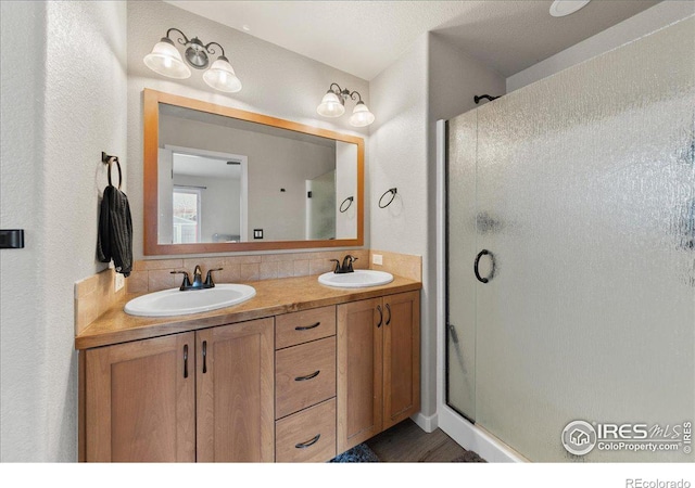 bathroom with double vanity, a stall shower, and a sink