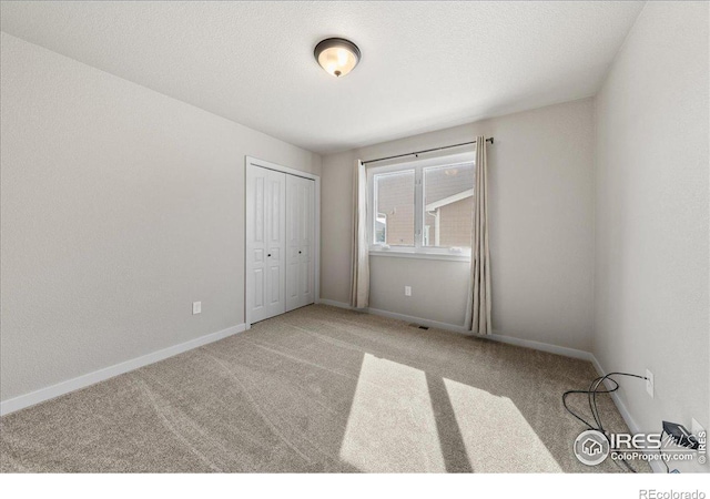 carpeted empty room with a textured ceiling, visible vents, and baseboards