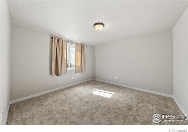 carpeted empty room featuring baseboards and a textured ceiling