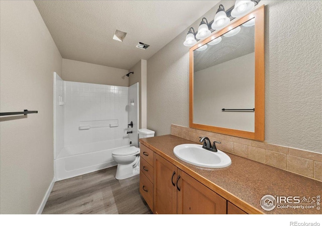 bathroom with a textured wall, toilet, vanity, a textured ceiling, and wood finished floors