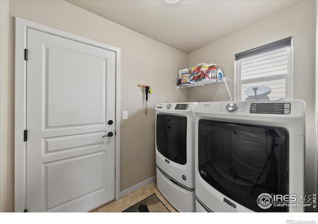 laundry area with laundry area, washing machine and dryer, and baseboards