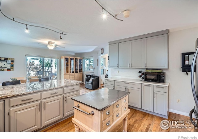 kitchen with a toaster, a ceiling fan, light wood-style floors, open floor plan, and gray cabinets