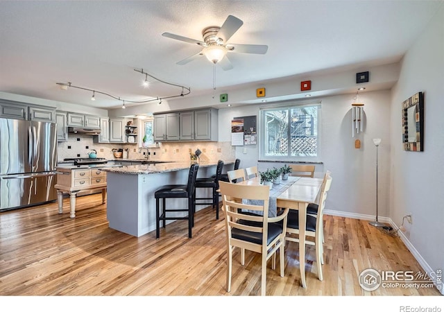 dining space featuring light wood finished floors, a ceiling fan, and baseboards