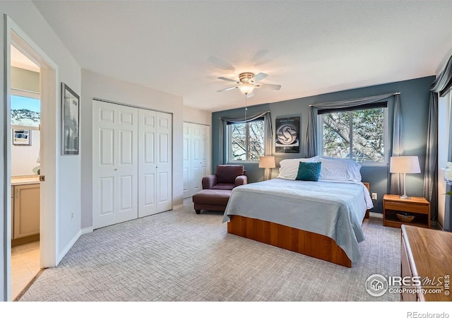 bedroom with a ceiling fan, multiple windows, baseboards, and two closets