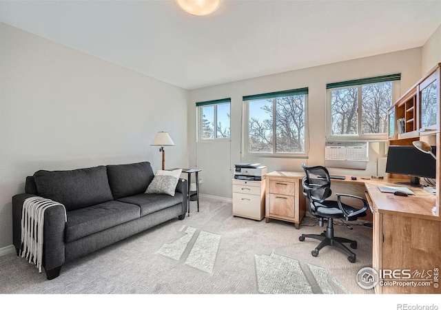 office area with a healthy amount of sunlight, light colored carpet, and baseboards