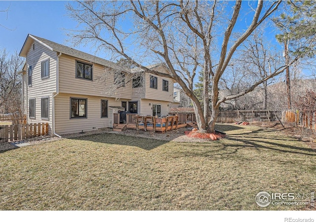 back of property featuring fence, a lawn, and a wooden deck