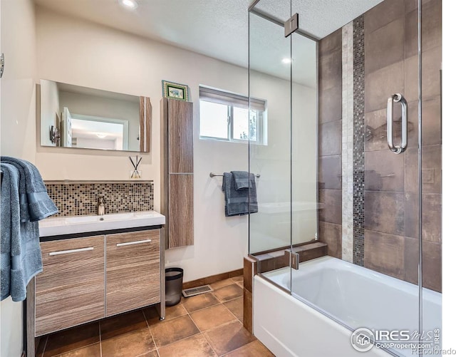 bathroom featuring tasteful backsplash, visible vents, combined bath / shower with glass door, vanity, and a textured ceiling