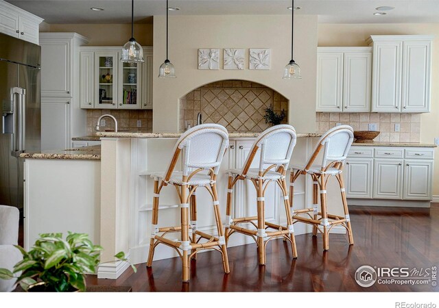 kitchen featuring decorative backsplash, light stone counters, glass insert cabinets, and recessed lighting
