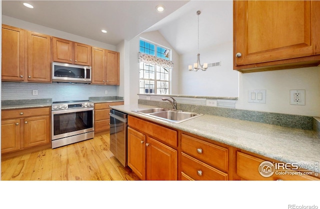 kitchen with light wood finished floors, lofted ceiling, visible vents, appliances with stainless steel finishes, and a sink