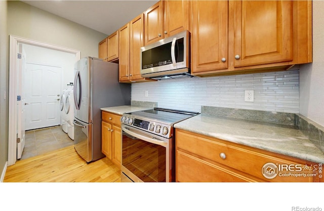 kitchen with stainless steel appliances, light countertops, washer and clothes dryer, and decorative backsplash