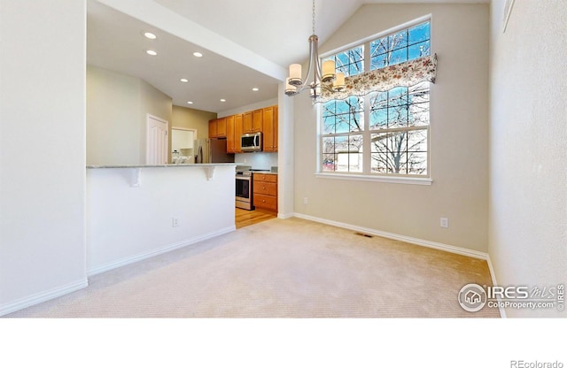 kitchen featuring appliances with stainless steel finishes, a wealth of natural light, brown cabinetry, and a kitchen bar