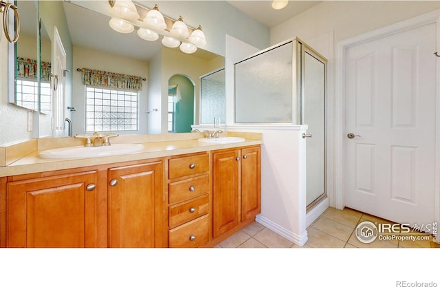 bathroom featuring tile patterned flooring, a sink, a shower stall, and double vanity