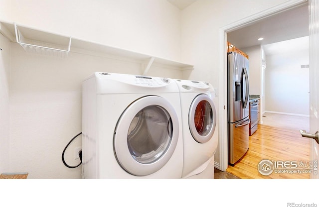 laundry area with light wood-type flooring, laundry area, independent washer and dryer, and baseboards