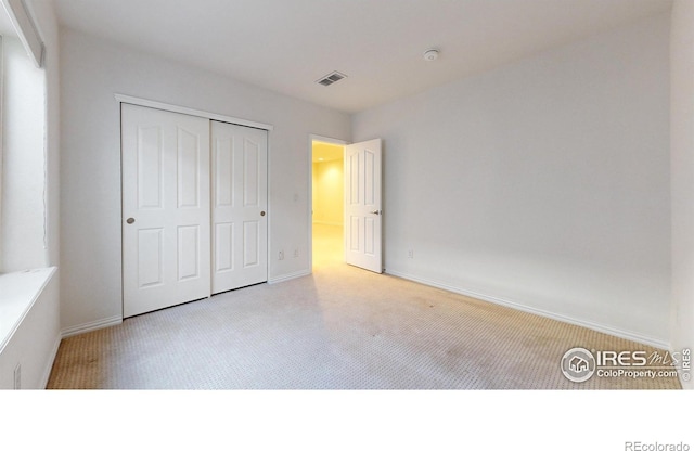 unfurnished bedroom with carpet, a closet, visible vents, and baseboards