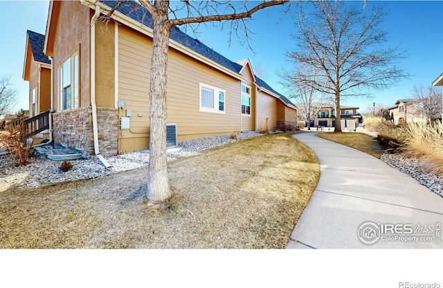 view of side of property featuring stone siding, stucco siding, and a yard