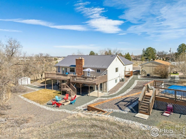 back of house featuring a patio, stairway, a chimney, and a wooden deck