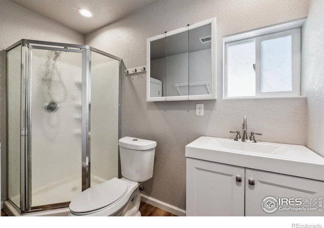 bathroom featuring wood finished floors, a stall shower, toilet, and a textured wall