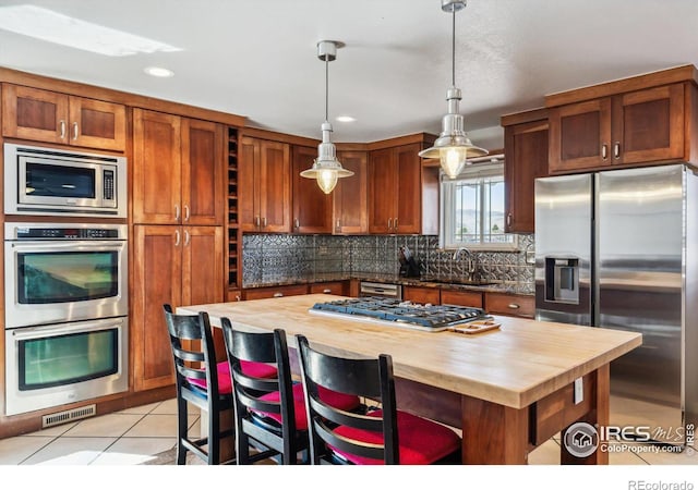 kitchen featuring a sink, stainless steel appliances, butcher block countertops, and light tile patterned floors