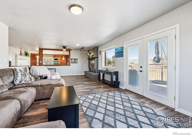 living room featuring ceiling fan, french doors, baseboards, and wood finished floors