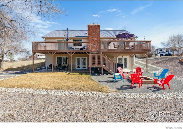 back of house with a wooden deck, french doors, a chimney, and an outdoor fire pit