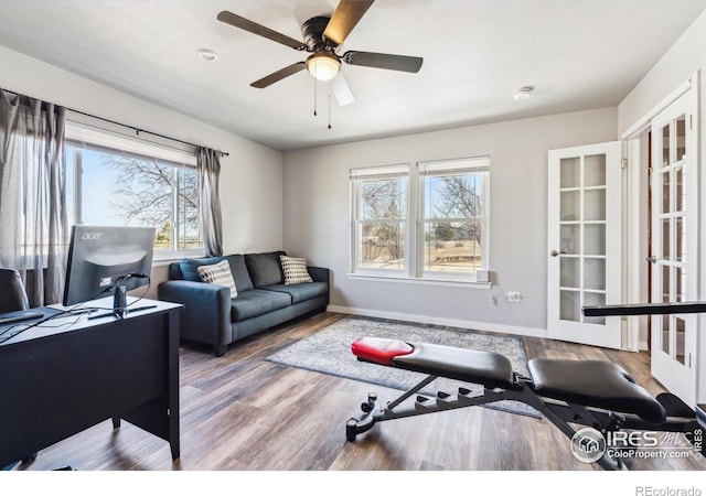 living area featuring wood finished floors, baseboards, and ceiling fan