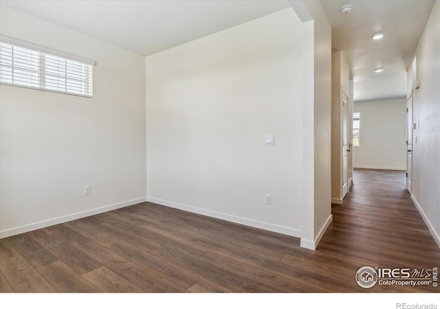 empty room featuring dark wood-style flooring and baseboards