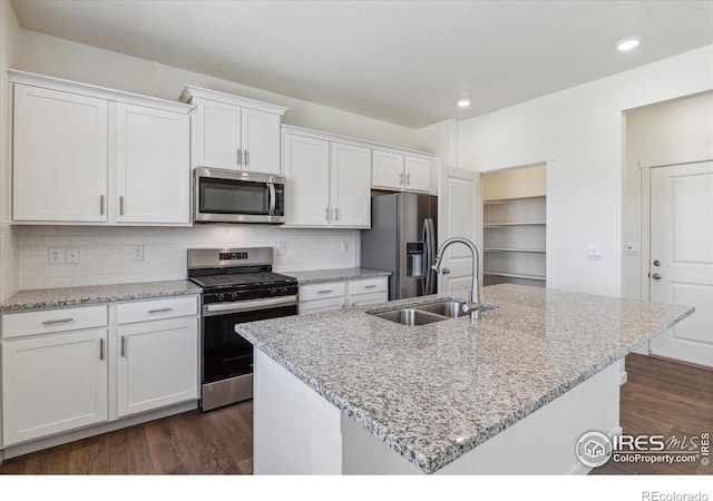 kitchen featuring dark wood-style flooring, backsplash, appliances with stainless steel finishes, white cabinetry, and a sink