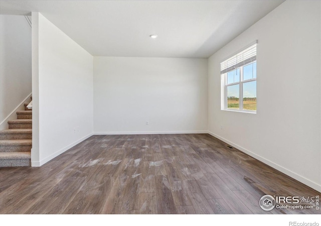 unfurnished room with stairway, baseboards, and wood finished floors