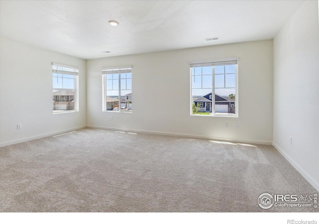 empty room featuring carpet, visible vents, and baseboards