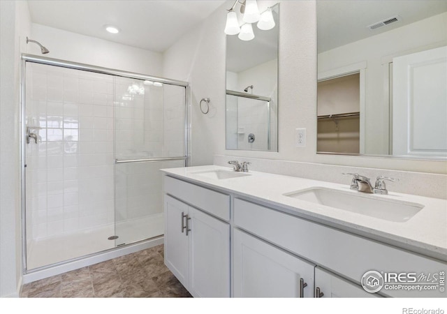 bathroom featuring double vanity, a stall shower, visible vents, and a sink