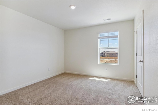 carpeted spare room with visible vents and baseboards