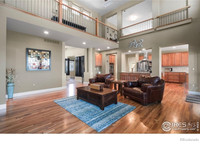 living room featuring visible vents, light wood-style flooring, and baseboards