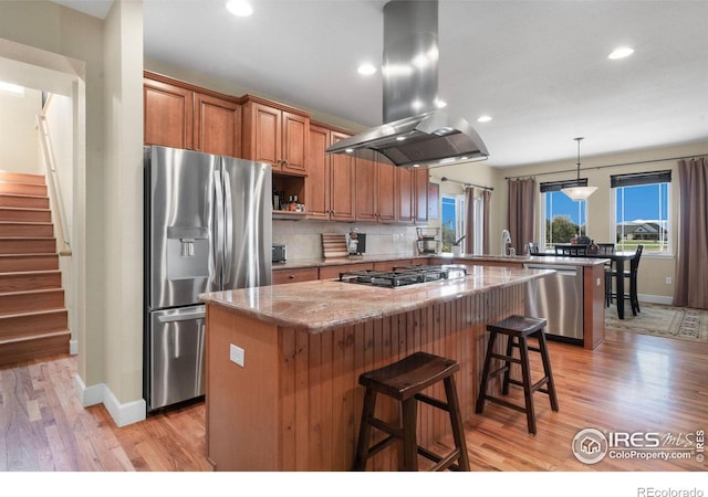 kitchen featuring stainless steel appliances, tasteful backsplash, a kitchen island, island range hood, and a peninsula