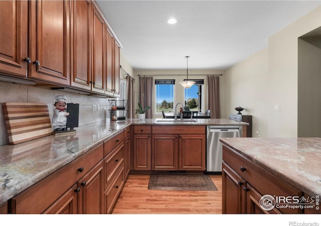 kitchen featuring a peninsula, stainless steel dishwasher, brown cabinetry, and a sink