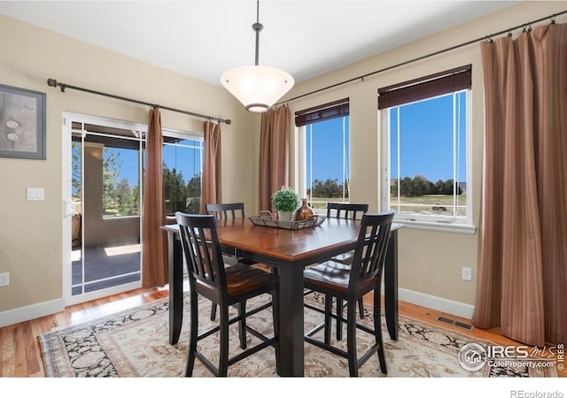 dining area with light wood-type flooring, visible vents, and baseboards