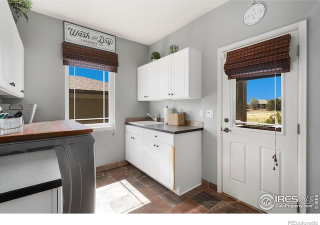 kitchen featuring white cabinetry, a sink, and baseboards