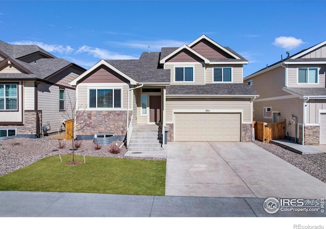 craftsman-style home with driveway, a garage, stone siding, fence, and a front lawn