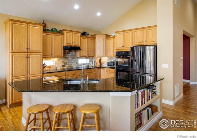 kitchen with visible vents, a spacious island, a sink, stainless steel appliances, and backsplash