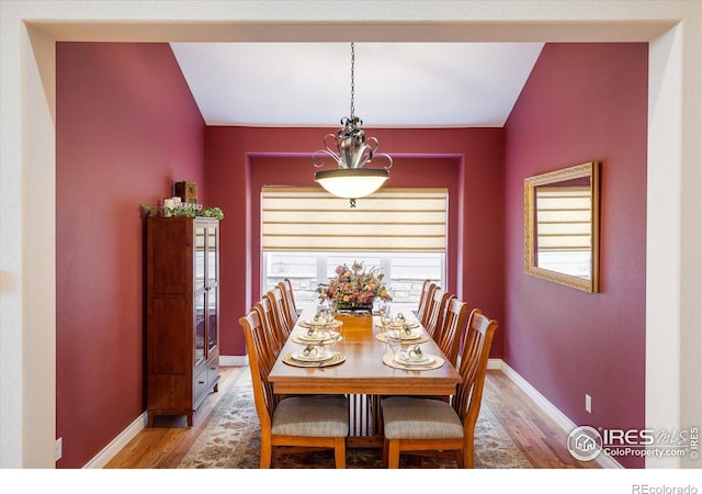 dining room with baseboards, lofted ceiling, and light wood-style flooring